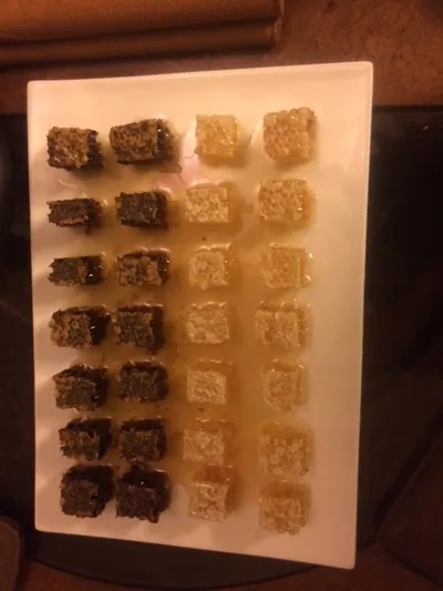 A tray of cut honeycomb pieces drizzled with honey