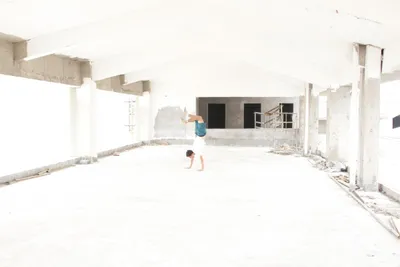 A person doing a handstand in a bright, empty unfinished building